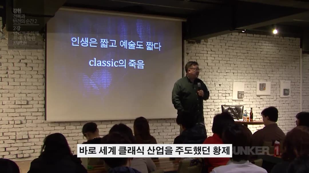 강연자가 스크린 앞에 서서 청중을 향해 이야기하고 있으며, 스크린에는 '인생은 짧고 예술도 짧다'라는 문구가 적혀 있습니다.
