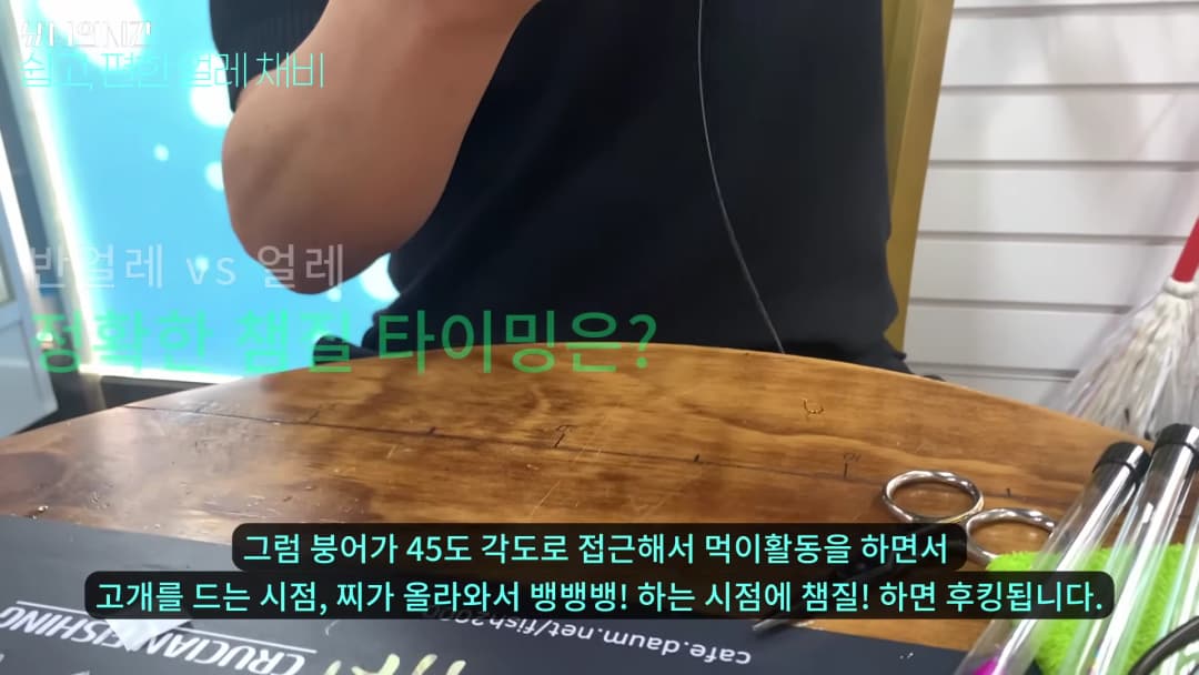 낚시 전문가가 테이블 앞에서 낚싯줄과 도구를 이용해 채비법을 설명하는 모습