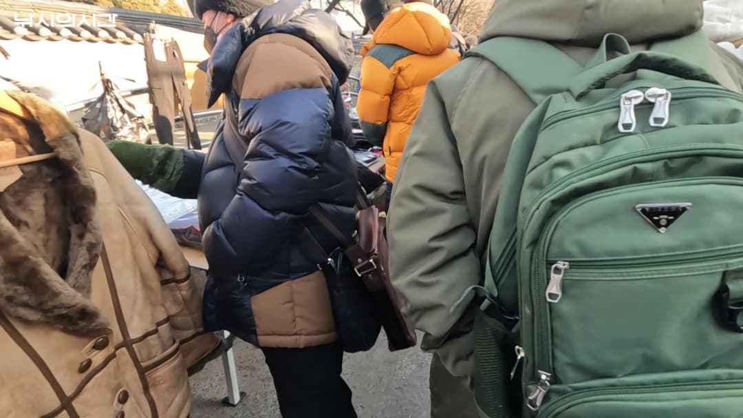 동묘 구제시장에서 두꺼운 겨울 외투를 입은 사람들이 옷과 물건을 구경하고 있는 모습