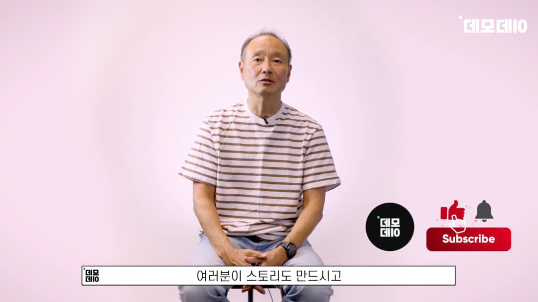 줄무늬 티셔츠를 입은 중년 남성이 밝은 배경 앞에서 앉아 이야기하고 있는 모습