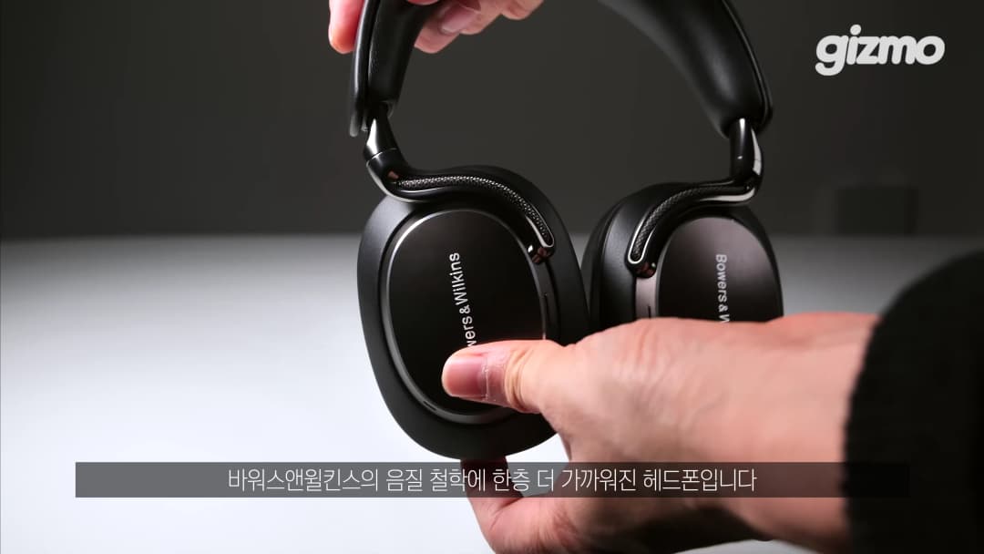 손으로 검은색 바워스앤윌킨스 헤드폰을 들고 있는 모습