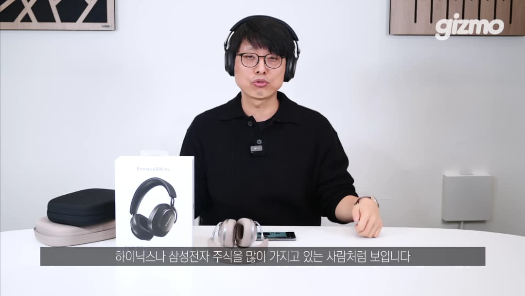 헤드폰을 착용한 안경 쓴 남성이 책상 앞에 앉아 제품을 소개하는 모습